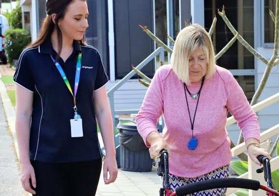 carer walking with older woman with frame